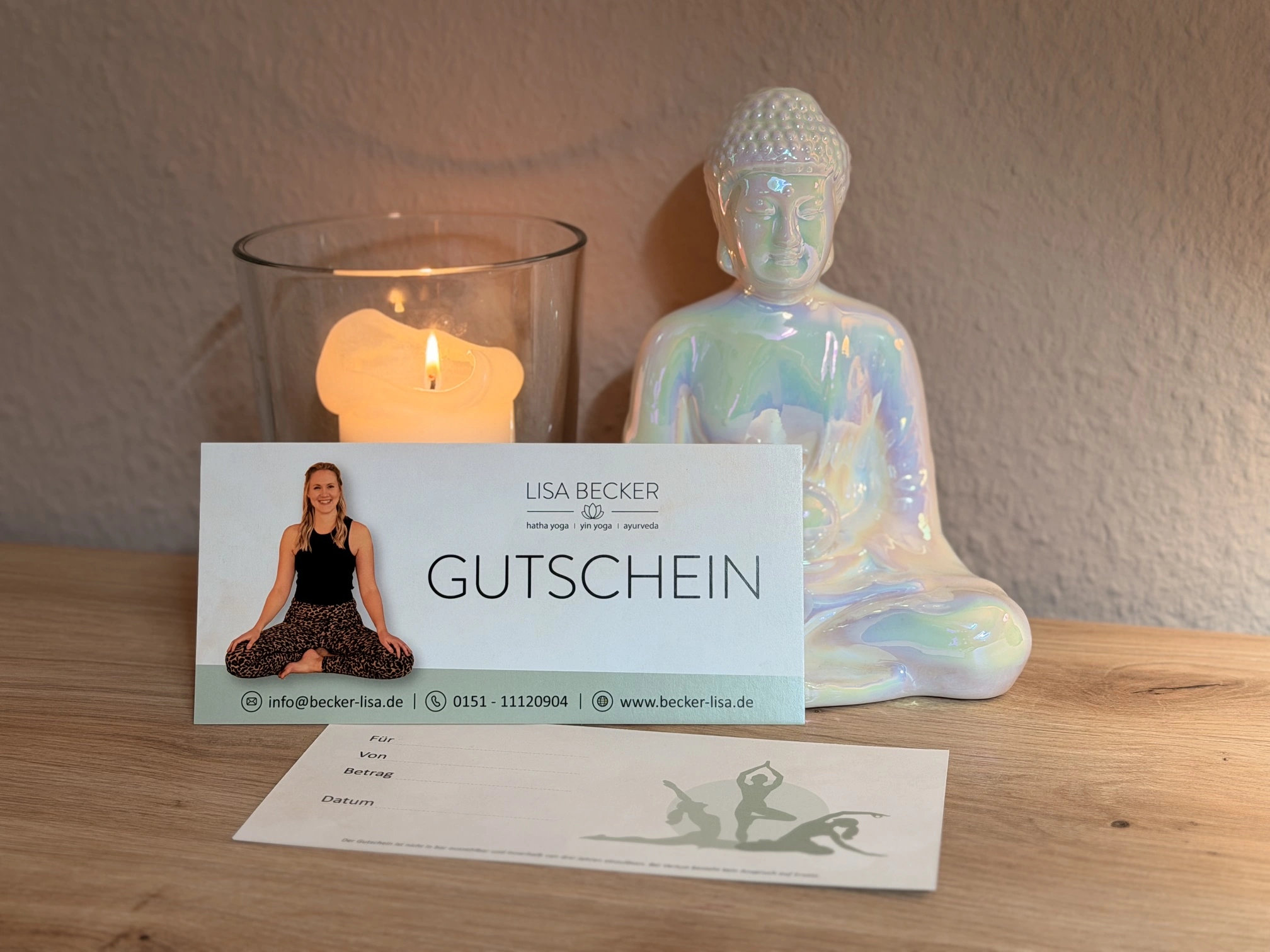 Yogagutschein von Lisa Becker neben einer Kerze und einer Buddha-Figur